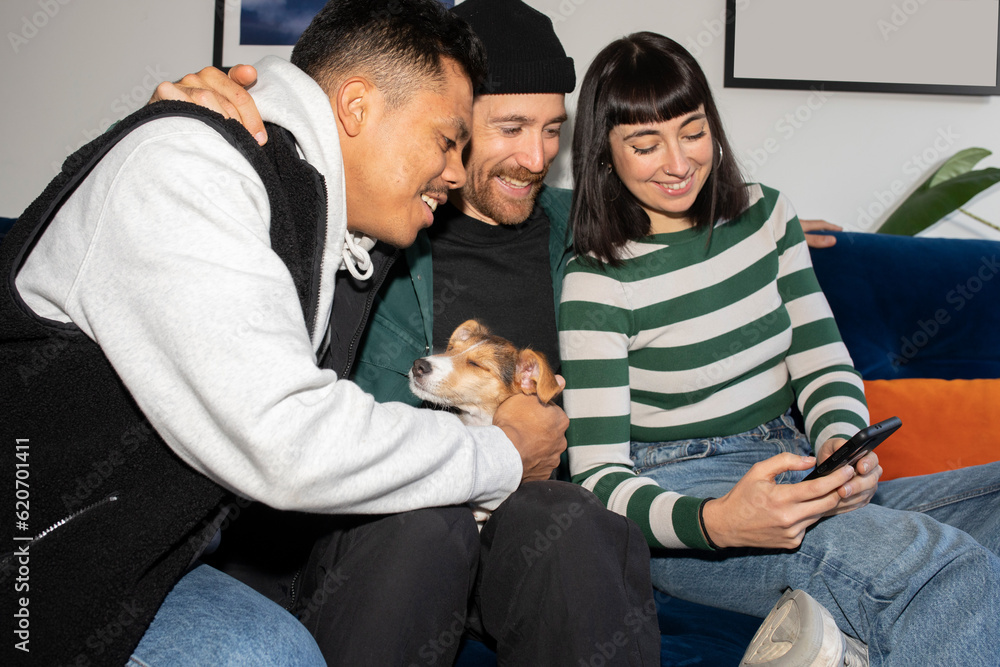 Friends laughing while using smartphone in a sofa Friends laughing while using smartphone in a sofa