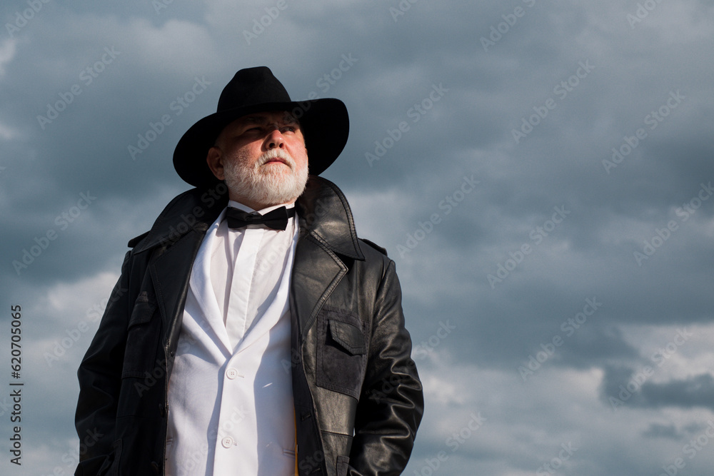 Fashion man in leather coat and hat outdoor. Cool gray bearded male confidently posing. Older grandfather, senior grandpa pensioner, retiree concept. Fashion man in leather coat and hat outdoor. Cool gray bearded male confidently posing. Older grandfather, senior grandpa pensioner, retiree concept.