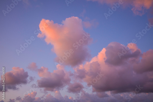 fluffige wolkenformationen am horizont, himmel an der küste mit abendrot bei leicht windiger brise, pink bis lila und orange gefärbte wolken in abendstimmung
