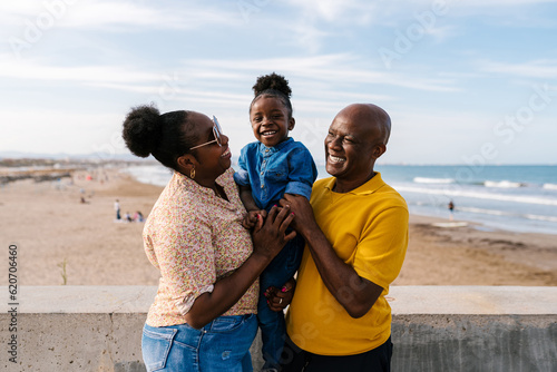 Happy black parents holding kid near sea photo