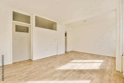 an empty room with white walls and wood flooring on the right, there is a door in the left corner