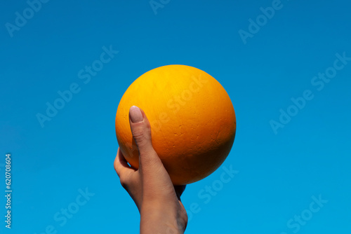 Hand holding a yellow ball and blue sky background