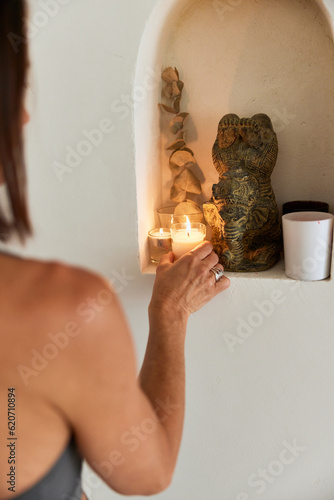 Faceless female putting aromatic candle on niche