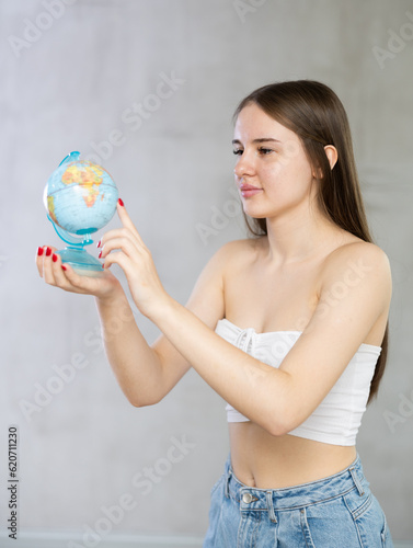 Portrait of a young student girl with a globe in her hands