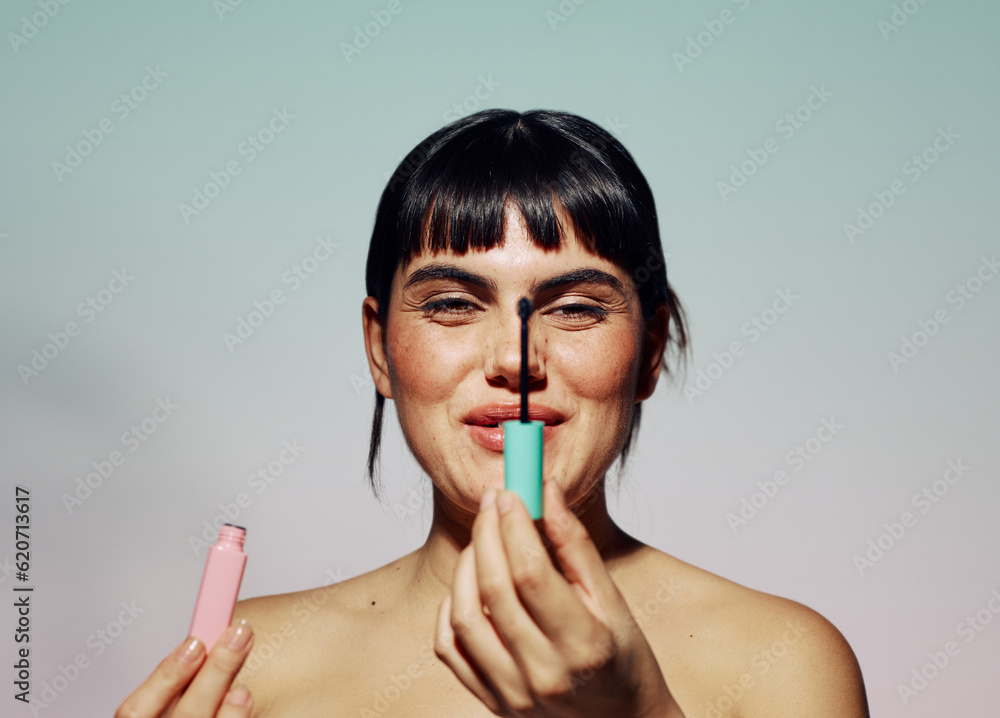 Playful, smiling woman holding mascara brush and looking at camera Playful, smiling woman holding mascara brush and looking at camera