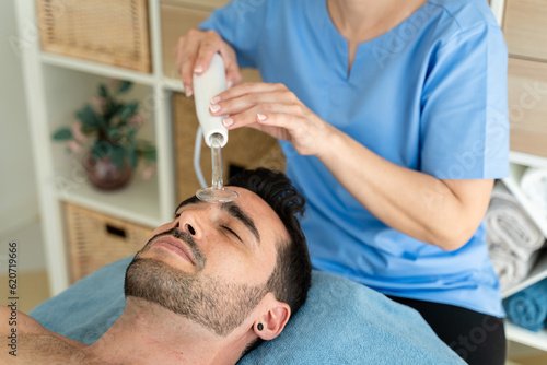 Female masseuse using high frequency device on male patient. photo