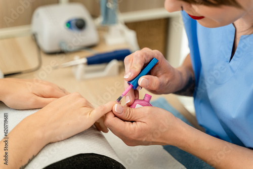 Female manicurist painting a client's nails. photo