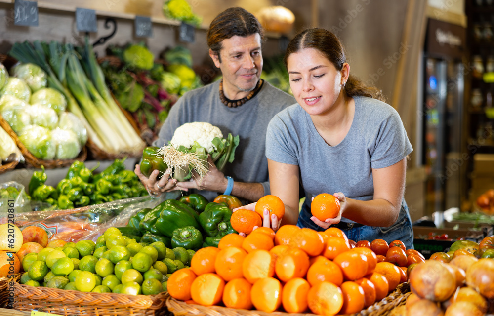 Husband and wife choose fresh fruits and vegetables together in a grocery supermarket