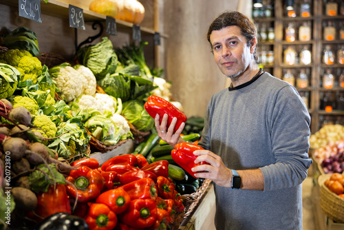 Caucasian man looking to buy red bell pepper in local vegetable market