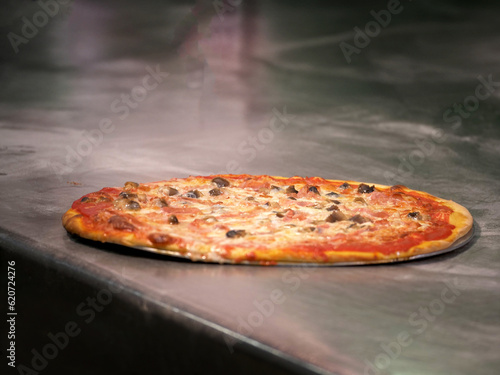 pizza margherita appena uscita dal forno su di una base di acciaio di una pizzeria photo
