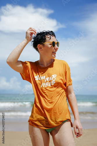 A woman with wet hair stands on the beach in summer photo