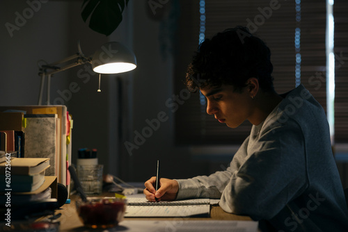 Teenage male studying late night at home