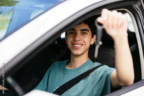 Smiling teen boy showing car keys in car photo