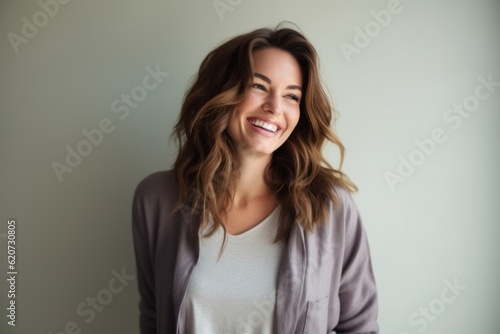 Lifestyle portrait photography of a grinning woman in her 30s wearing a chic cardigan against a minimalist or empty room background © Eber Braun