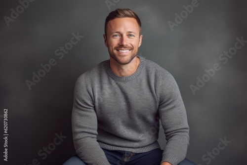 Portrait of a handsome young man in a gray sweater on a gray background