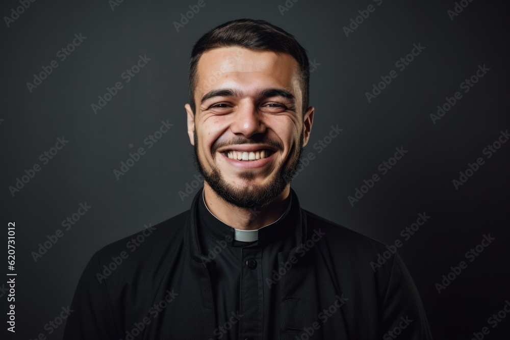 Portrait of a young smiling catholic priest on a dark background
