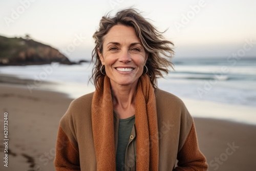 Medium shot portrait photography of a pleased woman in her 40s wearing a chic cardigan against a beach background