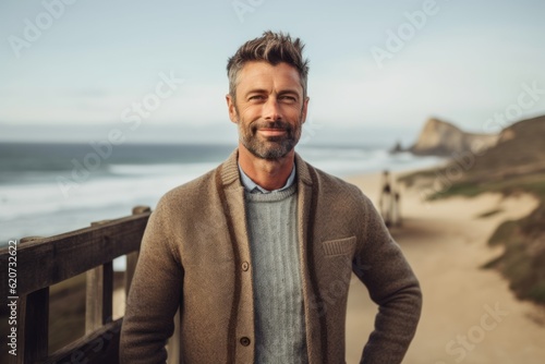 Portrait of handsome man standing on wooden terrace at the beach
