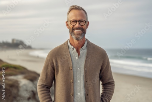 Portrait of handsome mature man with eyeglasses standing on beach