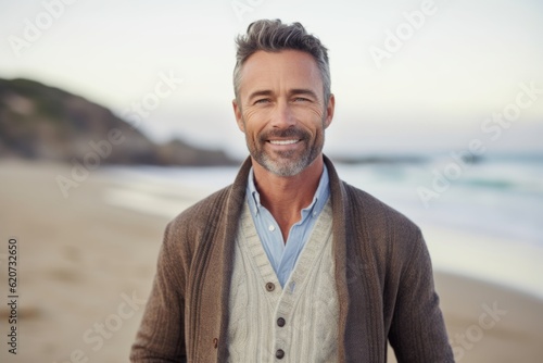 Portrait of smiling mature man standing on beach at seaside during sunny day