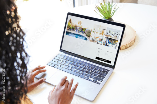 Black woman looking at vacation rental on computer at home photo