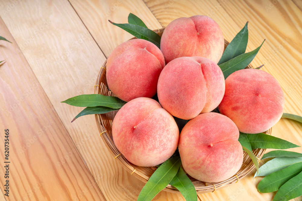 Peaches with leaves on the wooden table, Fresh pink Peach wooden basket plate in wooden Background. Peaches with leaves on the wooden table, Fresh pink Peach wooden basket plate in wooden Background.