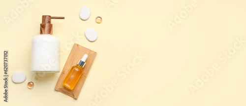 Bottles with liquid soap and serum with spa stones on beige background with space for text