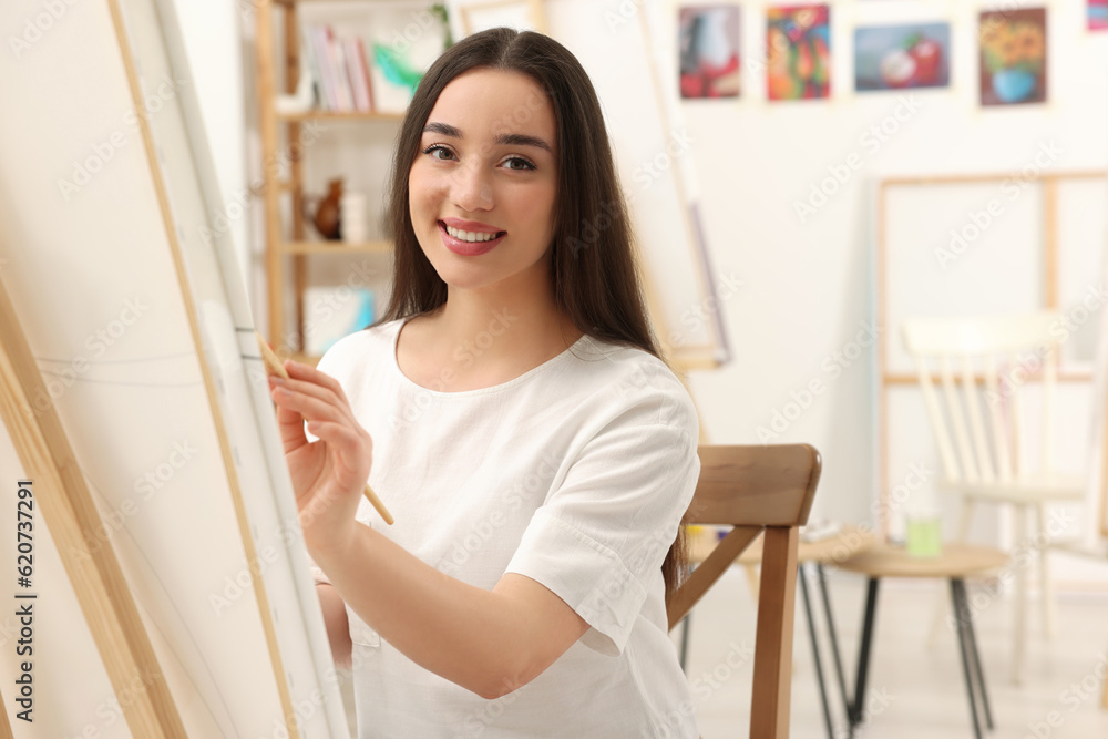Beautiful young woman painting with brush in studio. Creative hobby