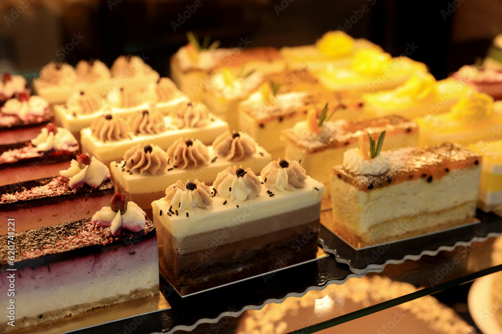 Different delicious cakes on counter in bakery shop, closeup