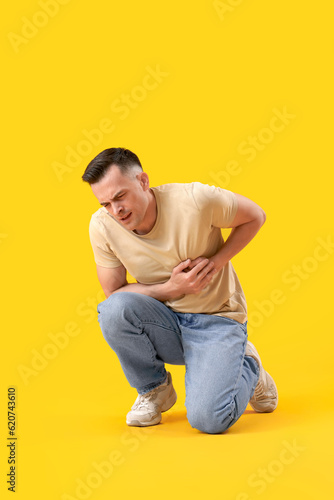Young man having heart attack on yellow background © Pixel-Shot