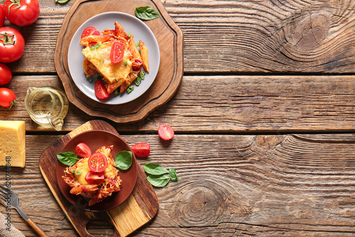 Plates of pasta with tomato sauce and cheese on wooden background