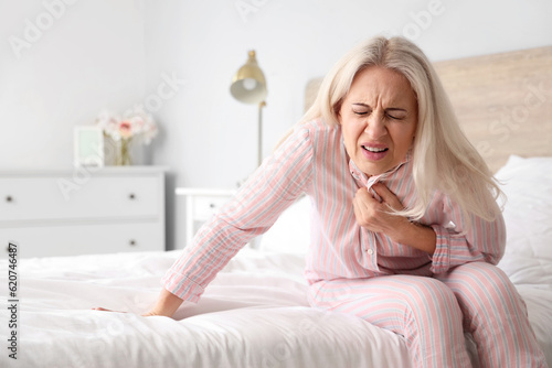 Mature woman having heart attack in bedroom
