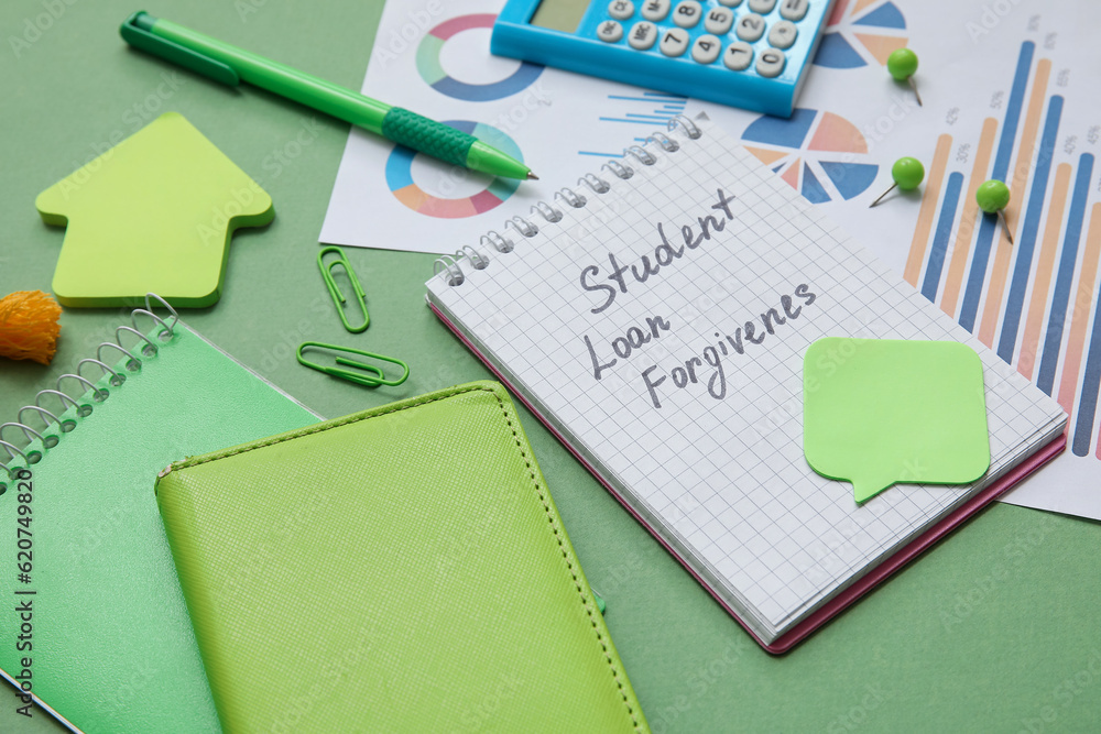Notepad with text STUDENT LOAN FORGIVENESS, calculator, charts and stationery on green background Notepad with text STUDENT LOAN FORGIVENESS, calculator, charts and stationery on green background