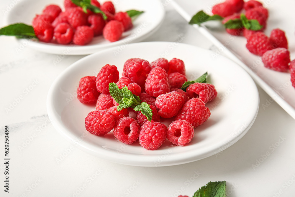 Plates with fresh raspberries and mint on white background Plates with fresh raspberries and mint on white background