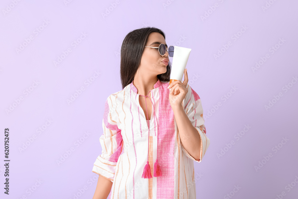 Beautiful young woman with sunscreen cream blowing kiss on lilac background Beautiful young woman with sunscreen cream blowing kiss on lilac background