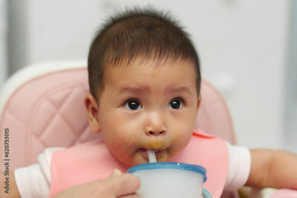 infant baby drinking a glass of water with a straw infant baby drinking a glass of water with a straw