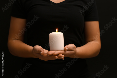 Canvas Print Woman holding burning candle on black background