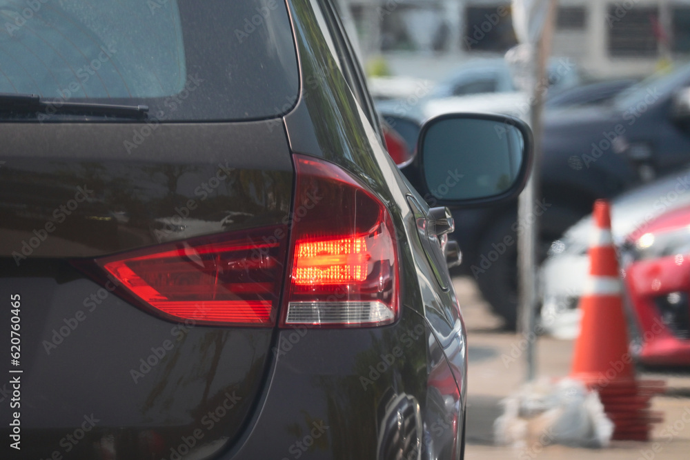 red tail light of brown car in large asphalt parking lot, transportation industry