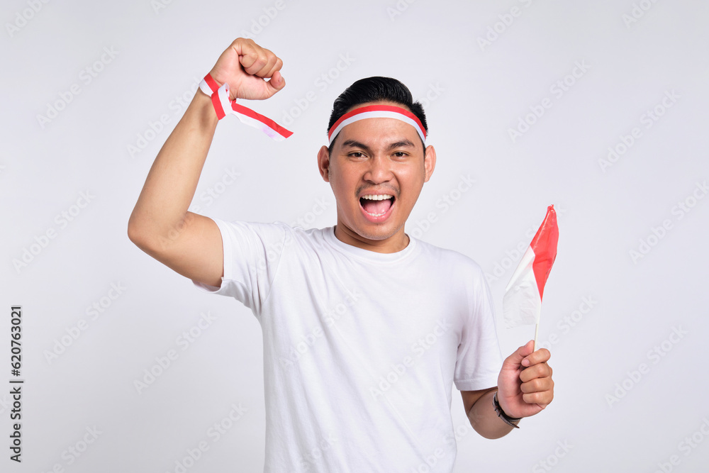 Excited young Asian men celebrate Indonesian independence day on 17 August by holding the Indonesian flag isolated over white background Excited young Asian men celebrate Indonesian independence day on 17 August by holding the Indonesian flag isolated over white background