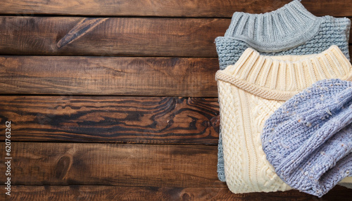 knitted sweaters on a wooden background, space for text
