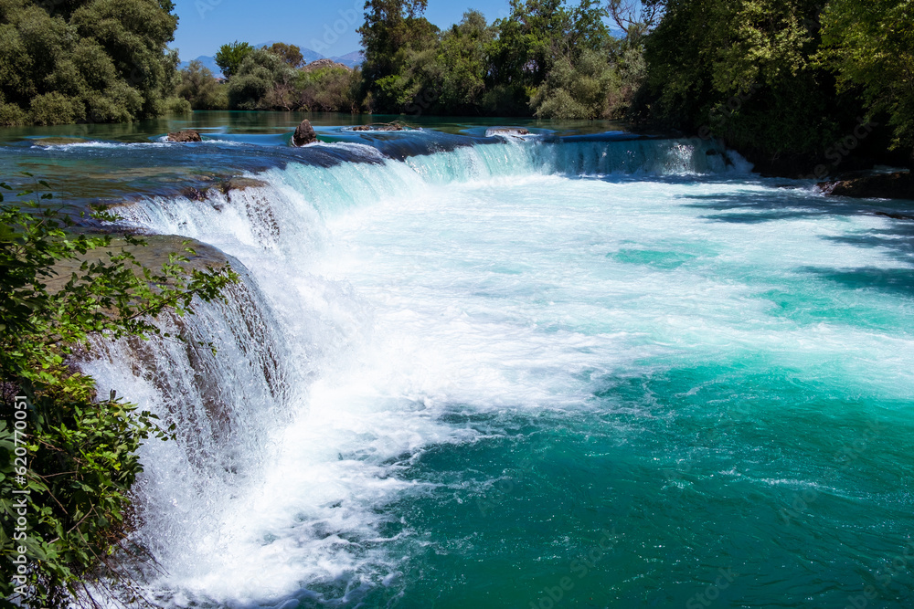 Manavgat waterfall Manavgat River is near the city of Side, 3 km north of Manavgat in Turkey. A wide stream of water falls from a low height. Manavgat waterfall Manavgat River is near the city of Side, 3 km north of Manavgat in Turkey. A wide stream of water falls from a low height.