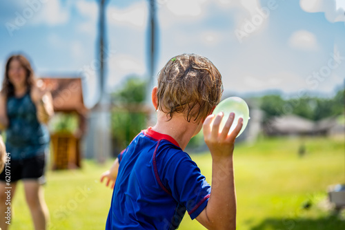 Young Caucasian boy taking aim to throw a water balloon. 