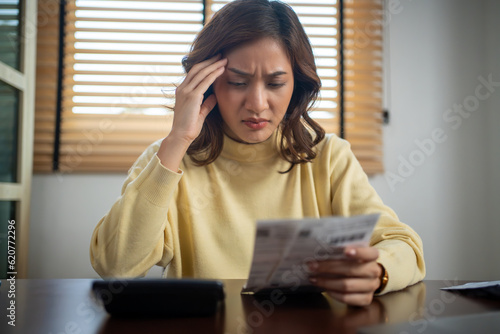 Asian woman calculating and stressing about household bills