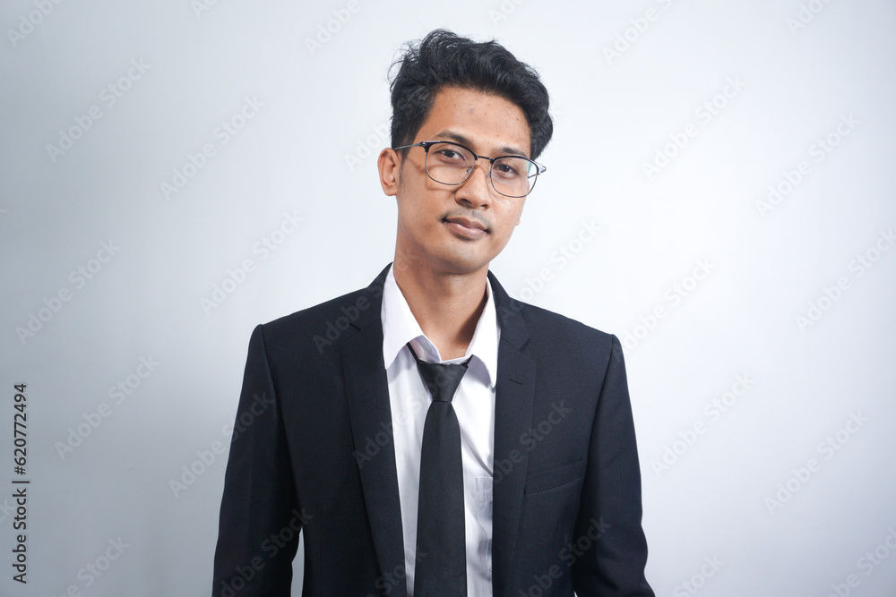 Indoor picture of young business man in glasses pictured isolated on white background looking straight at camera, showing confidence and providing stability for employees Indoor picture of young business man in glasses pictured isolated on white background looking straight at camera, showing confidence and providing stability for employees