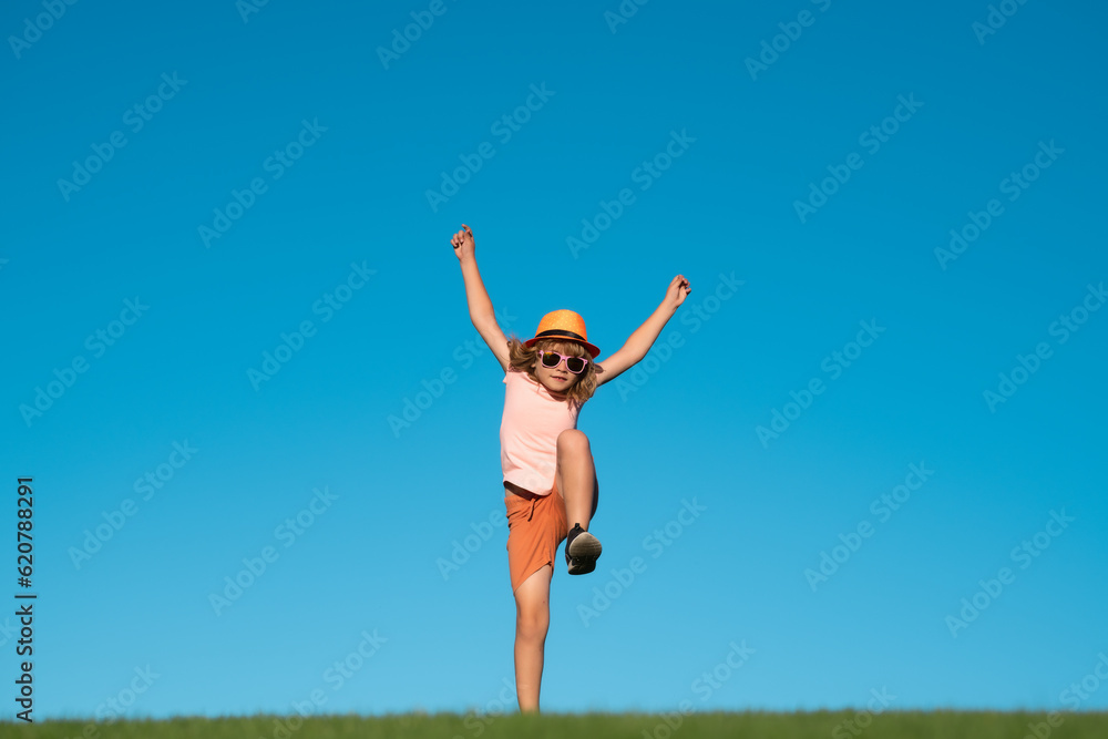 Kid boy running on green grass near blue sky in spring park. Child running outdoor. Healthy sport activity for children. Little boy at athletics competition race. Runner kids exercising. Kid boy running on green grass near blue sky in spring park. Child running outdoor. Healthy sport activity for children. Little boy at athletics competition race. Runner kids exercising.