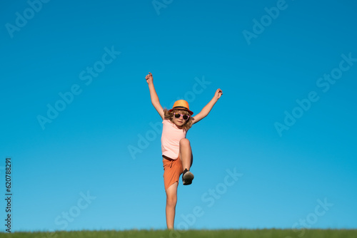 Kid boy running on green grass near blue sky in spring park. Child running outdoor. Healthy sport activity for children. Little boy at athletics competition race. Runner kids exercising.