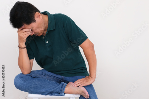 Man sitting alone on the floor looking very depressed with one hand supporting his head © Simon