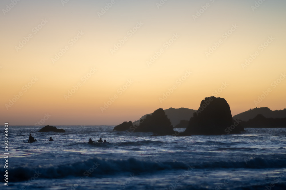 sunset over the sea with surfers surfing