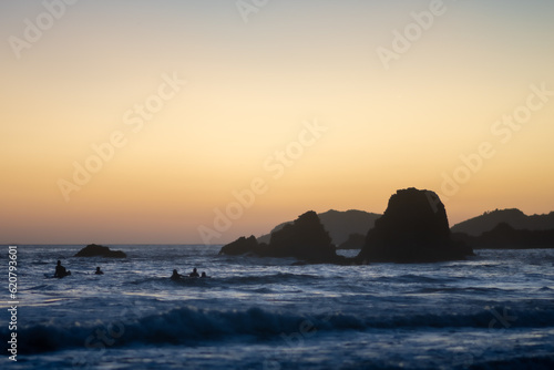 sunset over the sea with surfers surfing