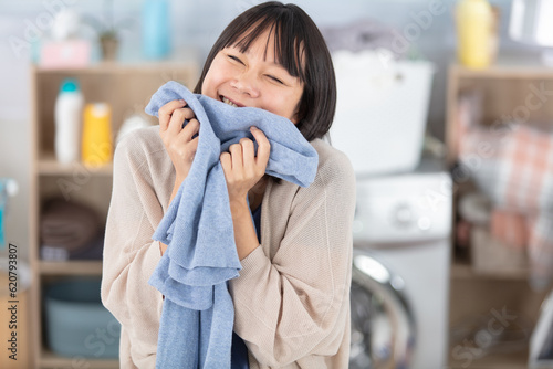 beautiful young woman is smelling clean clothes smiling